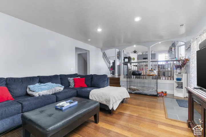 Spacious living area featuring wood-finish flooring, recessed lighting, and an open concept layout with arched architectural details