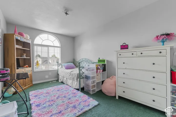 Room featuring a large arched window with horizontal blinds, light gray walls, and green carpeting