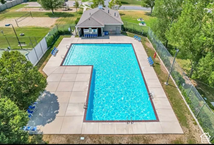 Resort-style pool with integrated steps, surrounding concrete decking, and adjacent clubhouse building