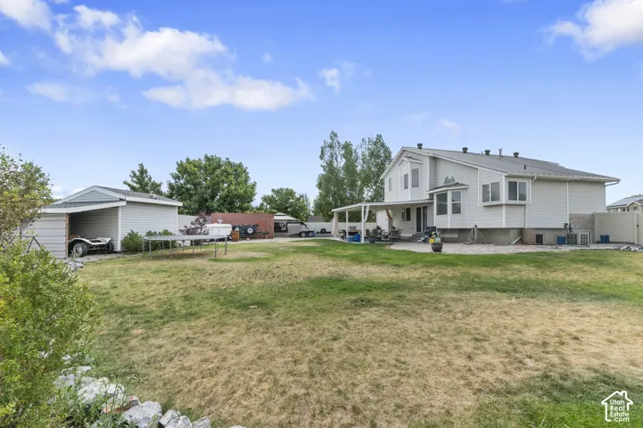 Expansive backyard featuring a large grass area and a dedicated storage shed with covered parking