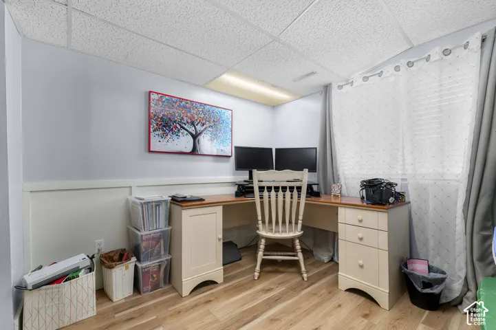 Room featuring wood-finish flooring, wainscoting, and a drop ceiling with recessed lighting