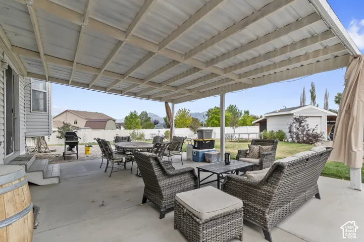 Covered concrete patio extending from the home, featuring a white metal roof and support beams