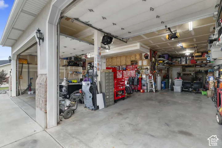 Spacious garage with multiple overhead doors, concrete flooring, and ample overhead lighting