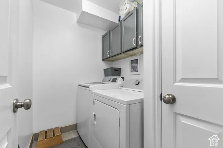 Dedicated laundry room featuring white appliances and upper cabinetry