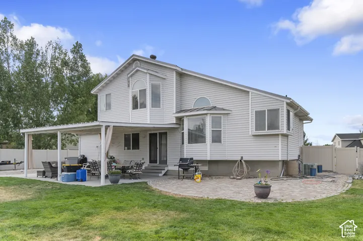 Rear exterior featuring a covered patio, extensive paver patio, bay windows, and siding facade