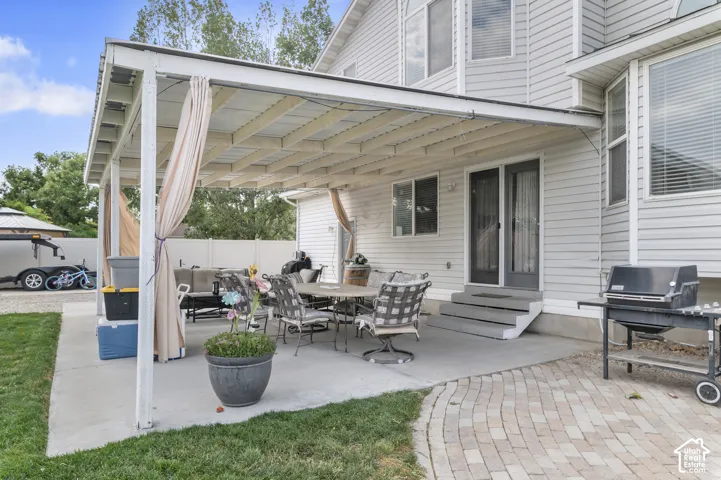 Expansive concrete patio featuring a white pergola with privacy curtains