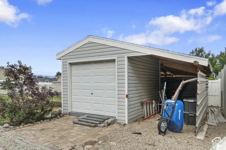 Detached garage with light gray siding and a white panel door
