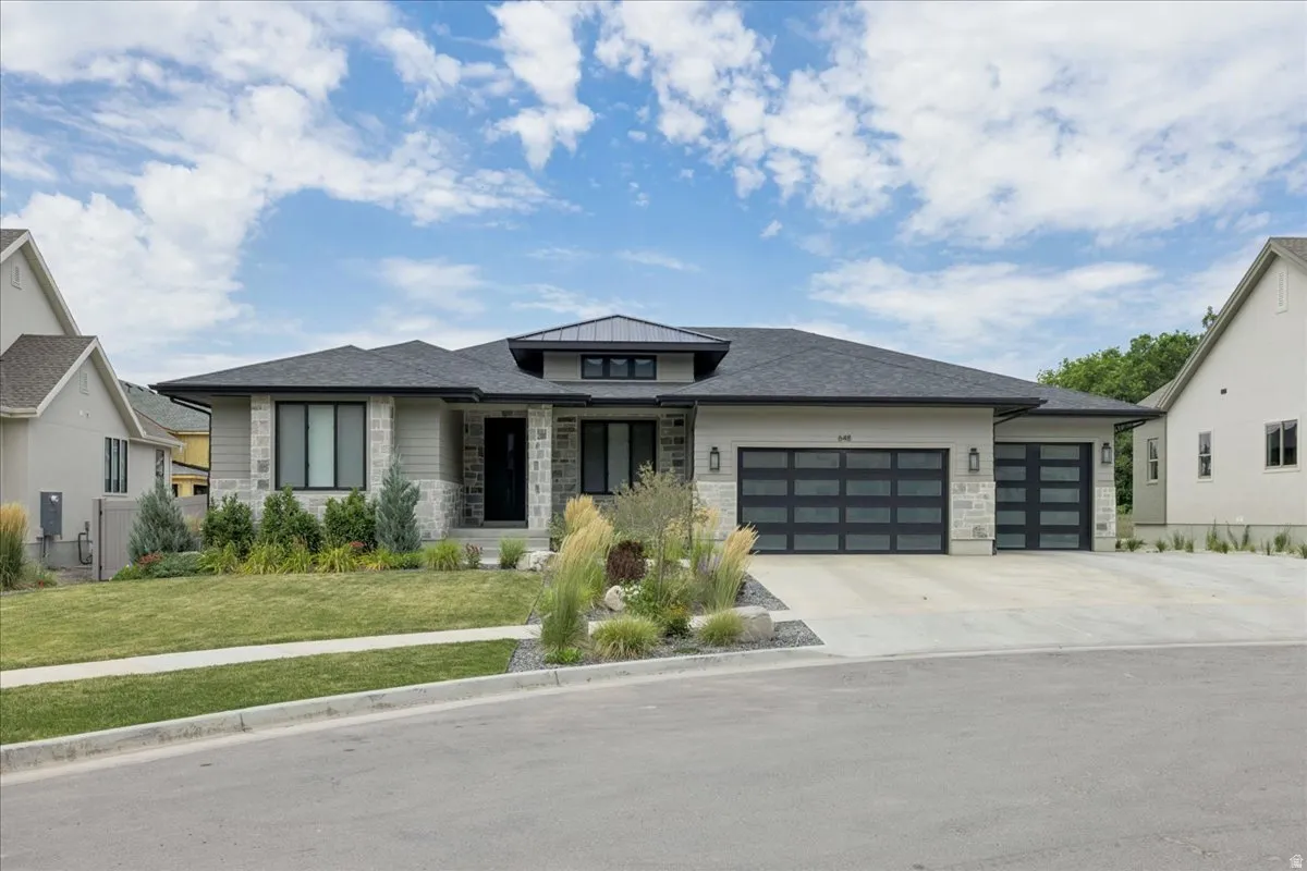 Contemporary exterior featuring a stone and stucco facade, a dark shingle roof, and a prominent front entry