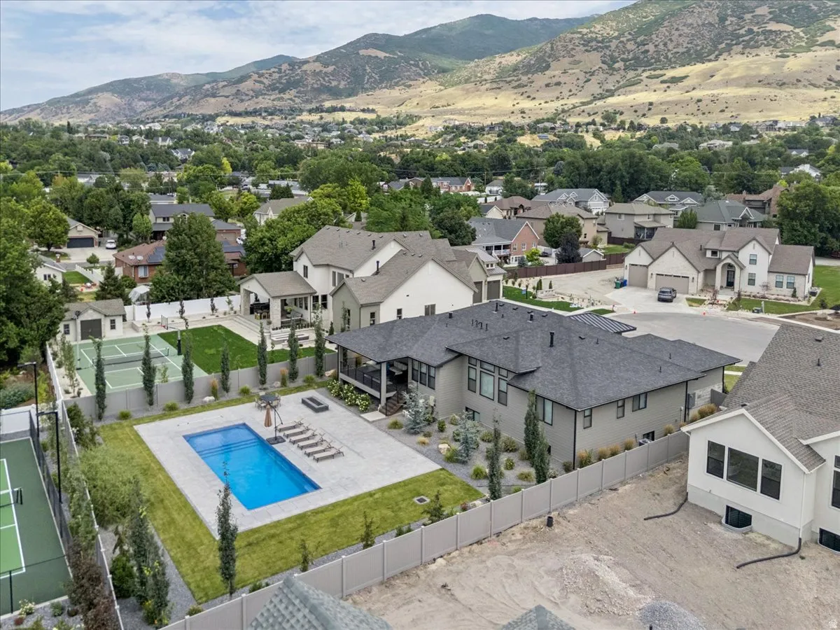 Property featuring a swimming pool, paved patio, full tennis court, expansive lawn, and mature landscaping