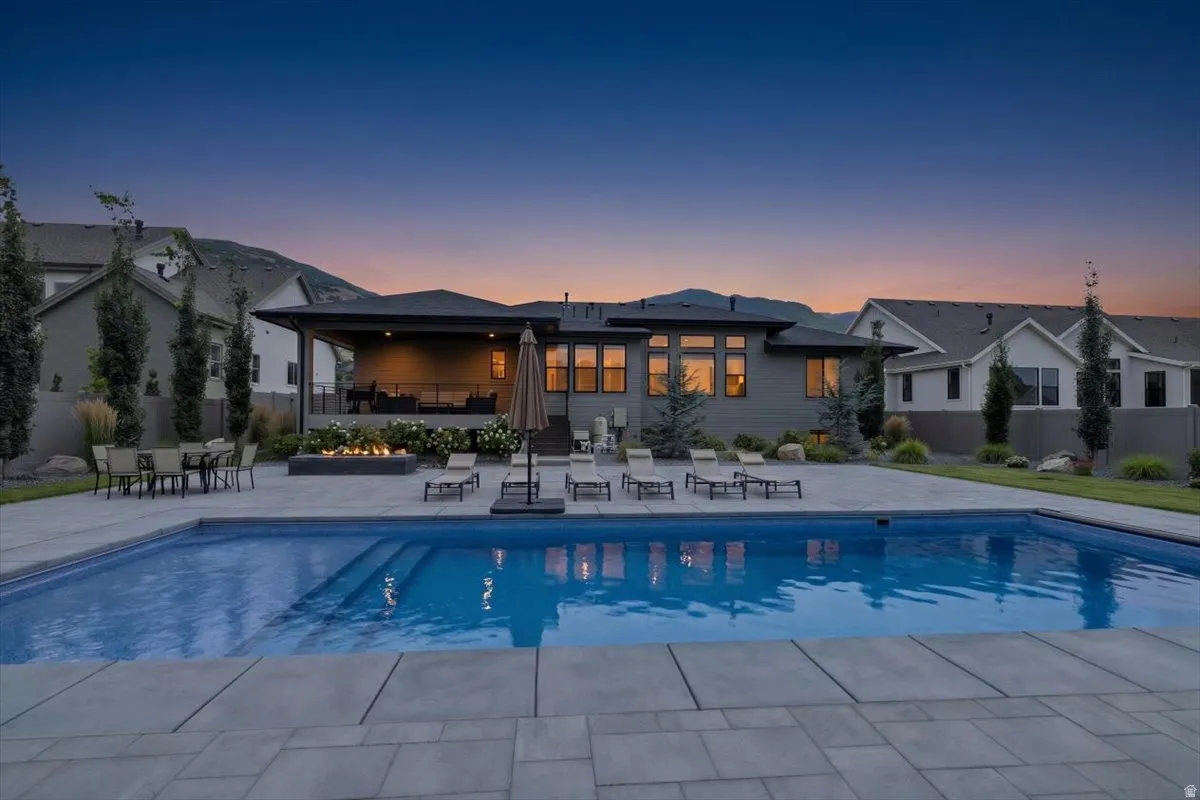 Expansive backyard featuring a rectangular swimming pool with integrated steps, surrounded by large format paver stones