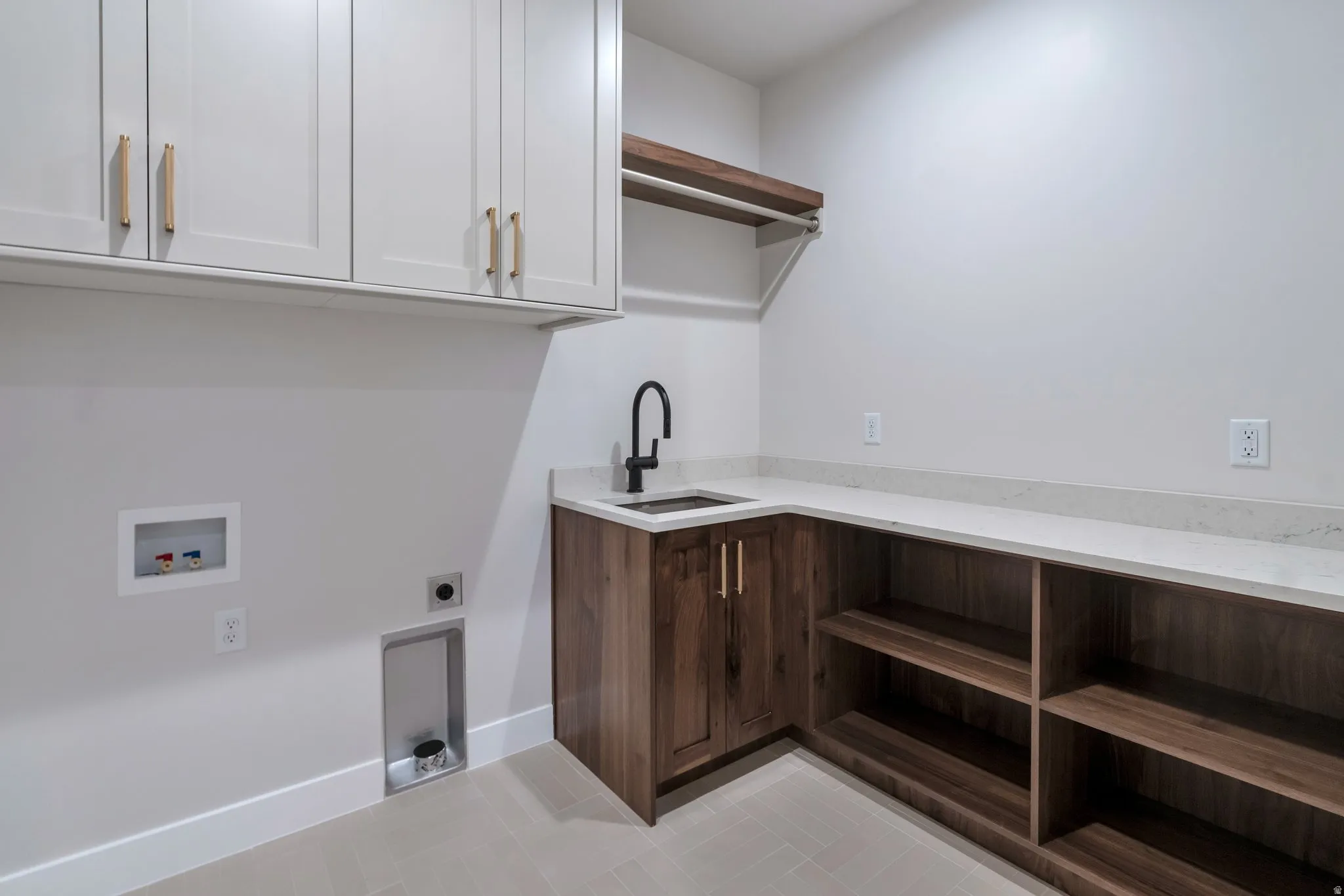 Laundry room featuring extensive cabinetry, a built-in sink with a matte black faucet, and ample counter space