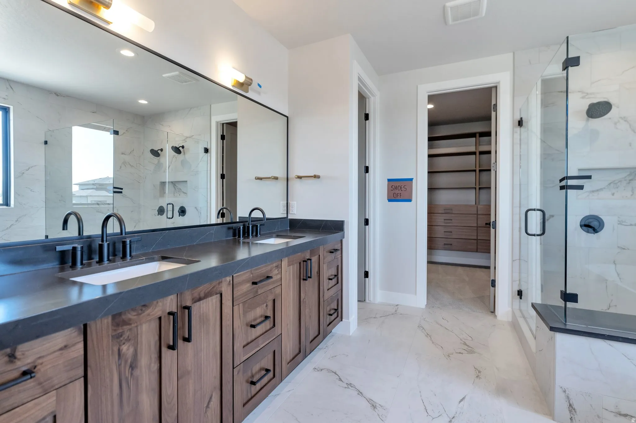 Double vanity with dark wood-finish cabinetry, integrated sinks, and matte black fixtures