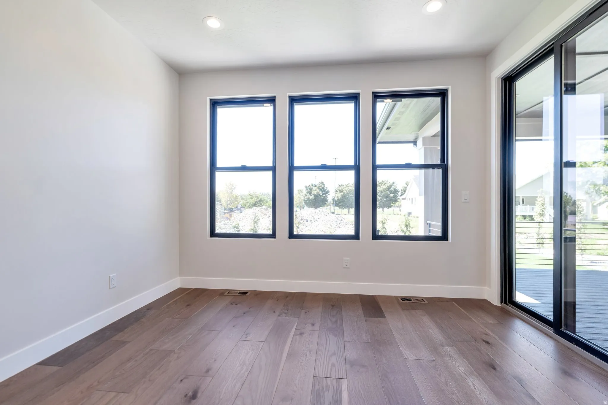 Spacious room featuring wood-finish flooring and a white baseboard trim