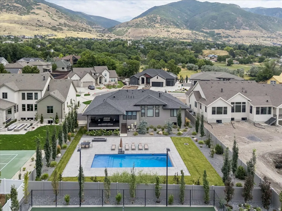 Expansive backyard featuring a large swimming pool with surrounding patio, a covered outdoor living area, and a dedicated tennis court