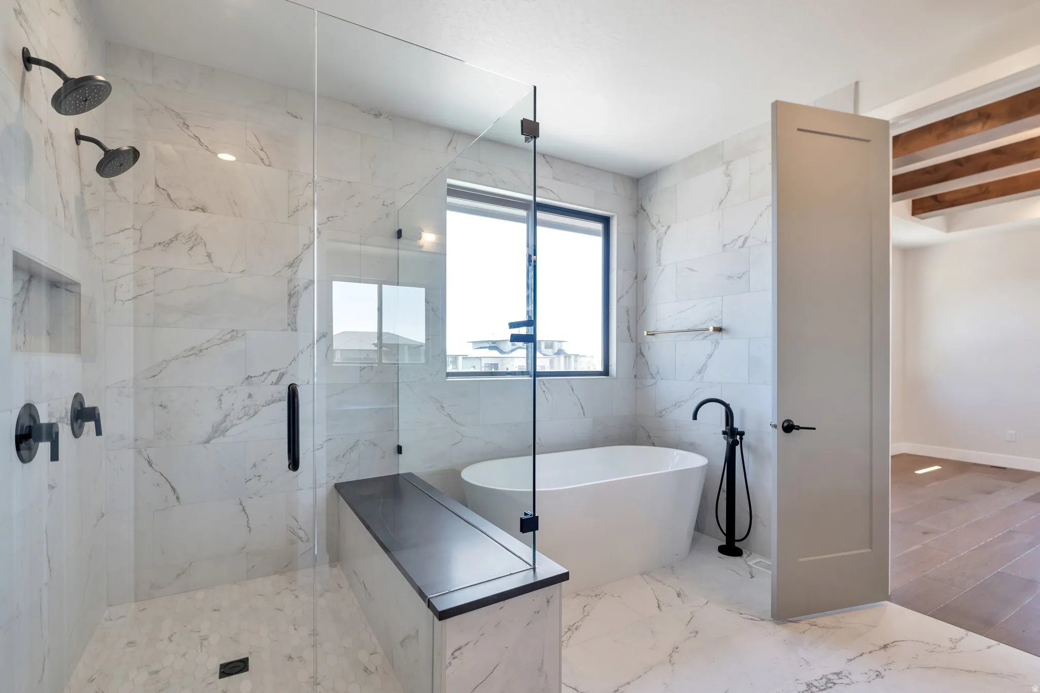 Contemporary bathroom with a glass-enclosed shower featuring dual matte black showerheads and a built-in bench