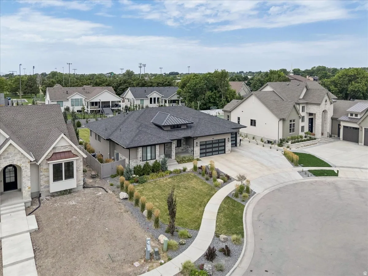 Contemporary ranch-style residence featuring a dark gray roof, stone accents, and a multi-car garage with frosted glass panels
