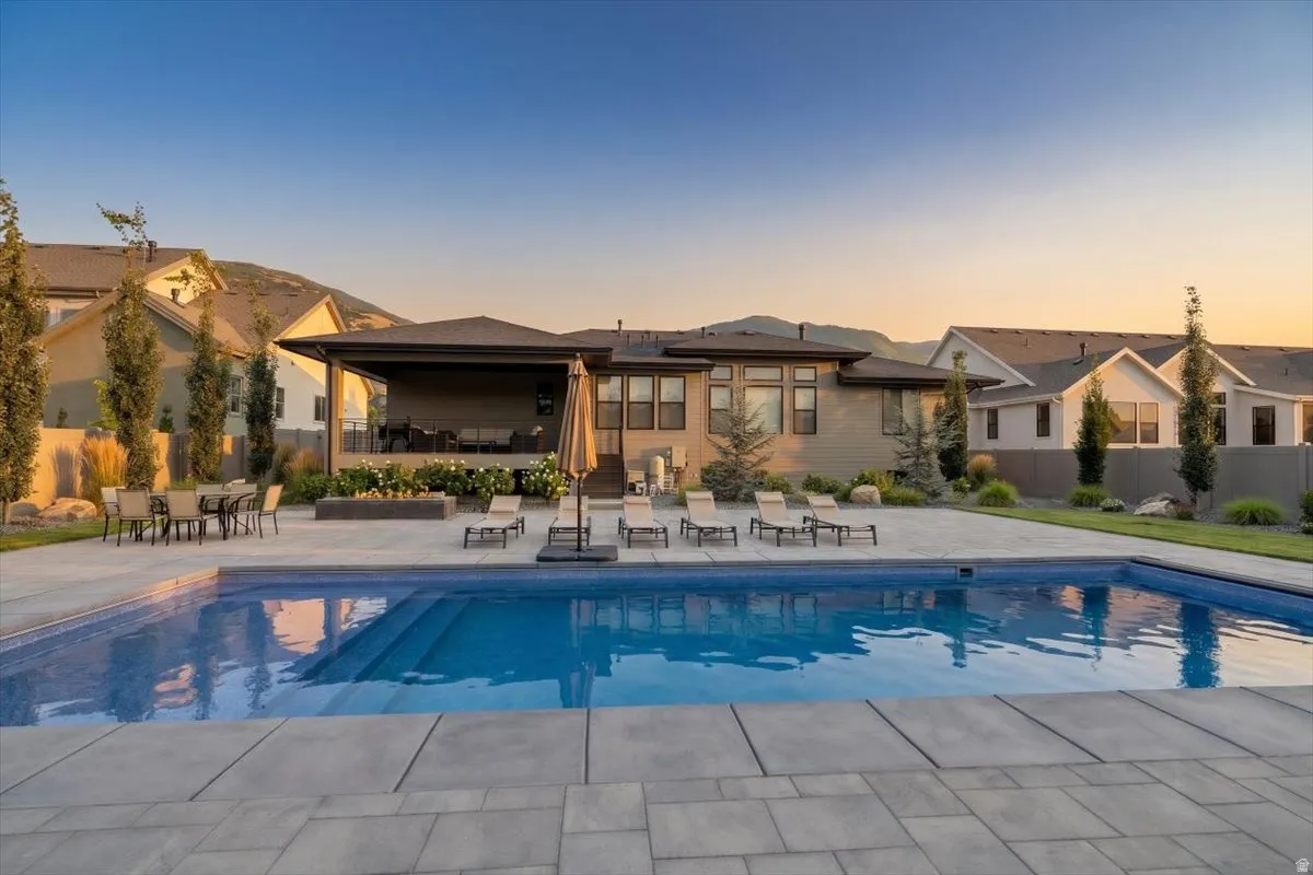Expansive outdoor living area featuring a large inground swimming pool with integrated steps, surrounded by a broad paver patio
