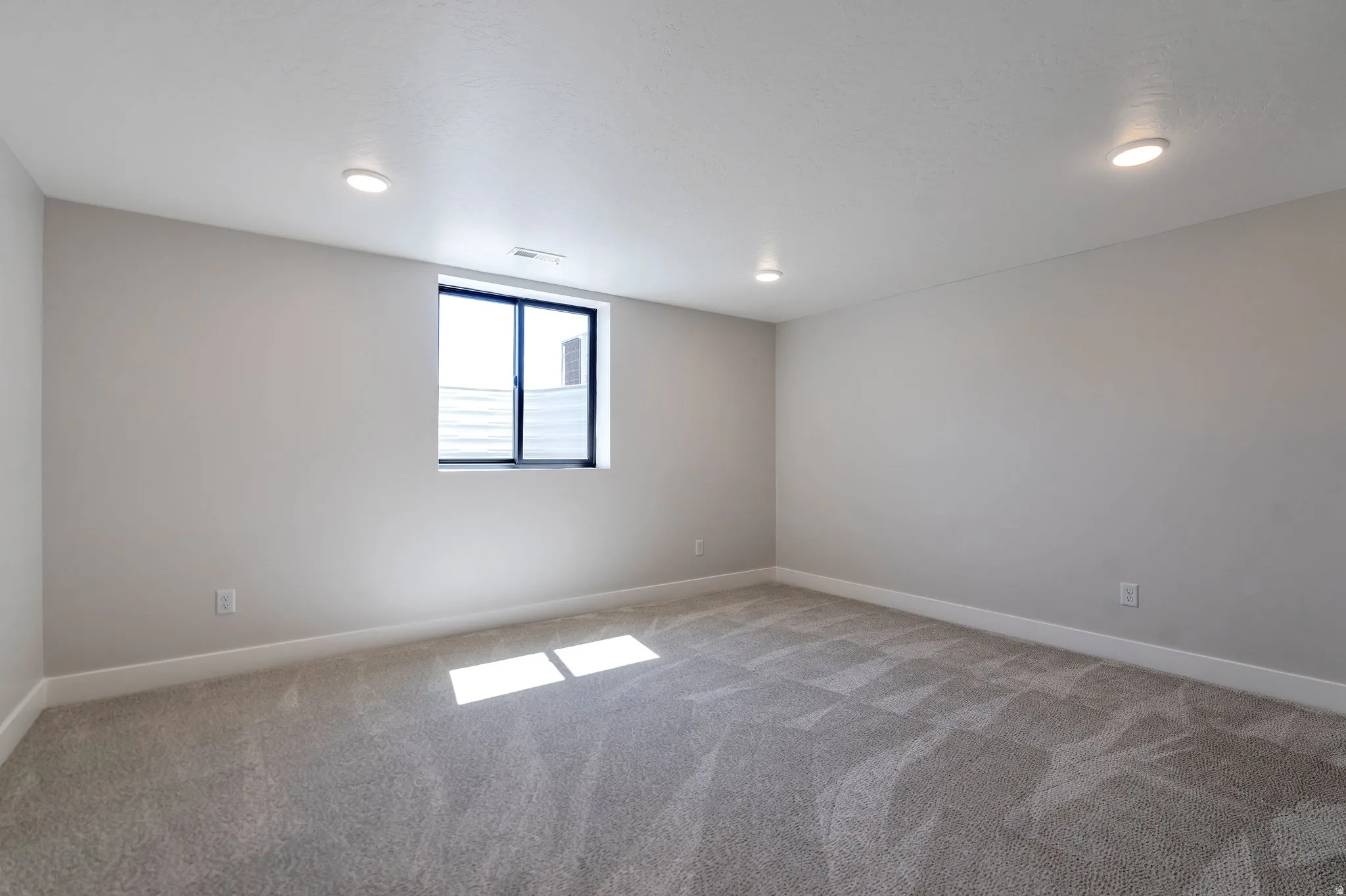 Spacious room featuring gray patterned carpeting and light gray walls