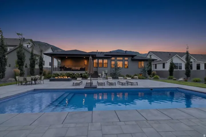 Expansive backyard featuring a rectangular swimming pool with integrated steps, surrounded by large format paver stones