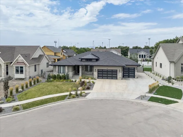 Contemporary single-story residence featuring a dark gray roof, stucco and stone exterior, two modern garage doors with frosted glass panels, an arched entry portico, and a concrete driveway