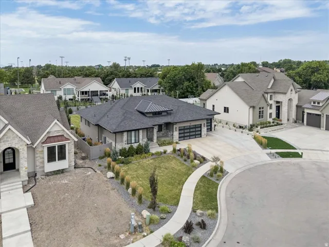 Contemporary ranch-style residence featuring a dark gray roof, stone accents, and a multi-car garage with frosted glass panels