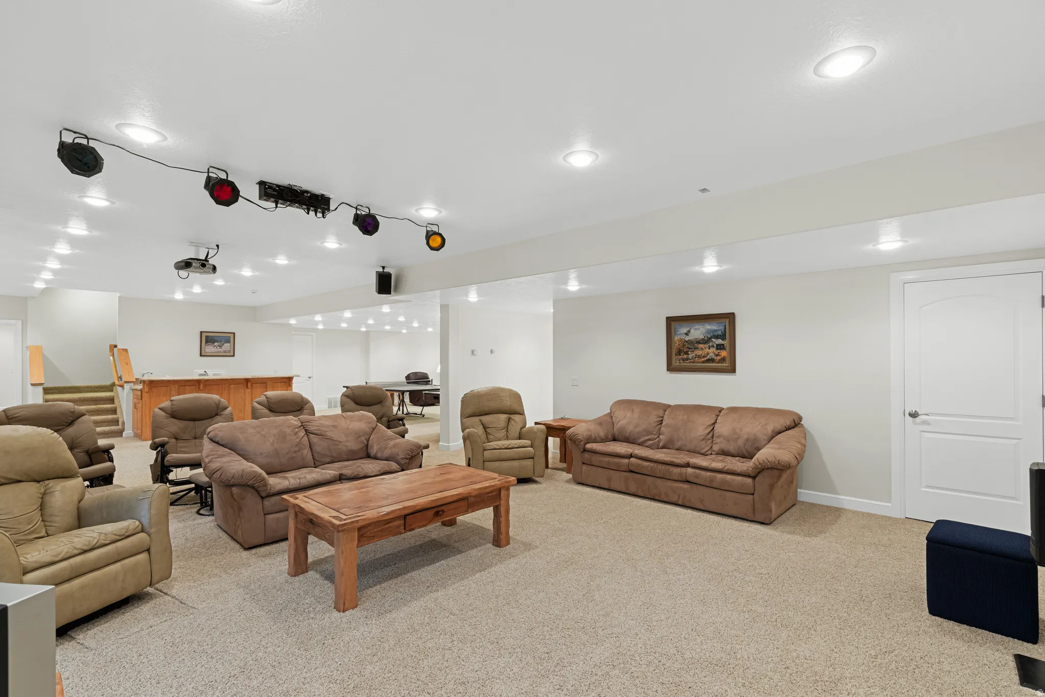 Carpeted recreation room featuring extensive recessed lighting and a projector system