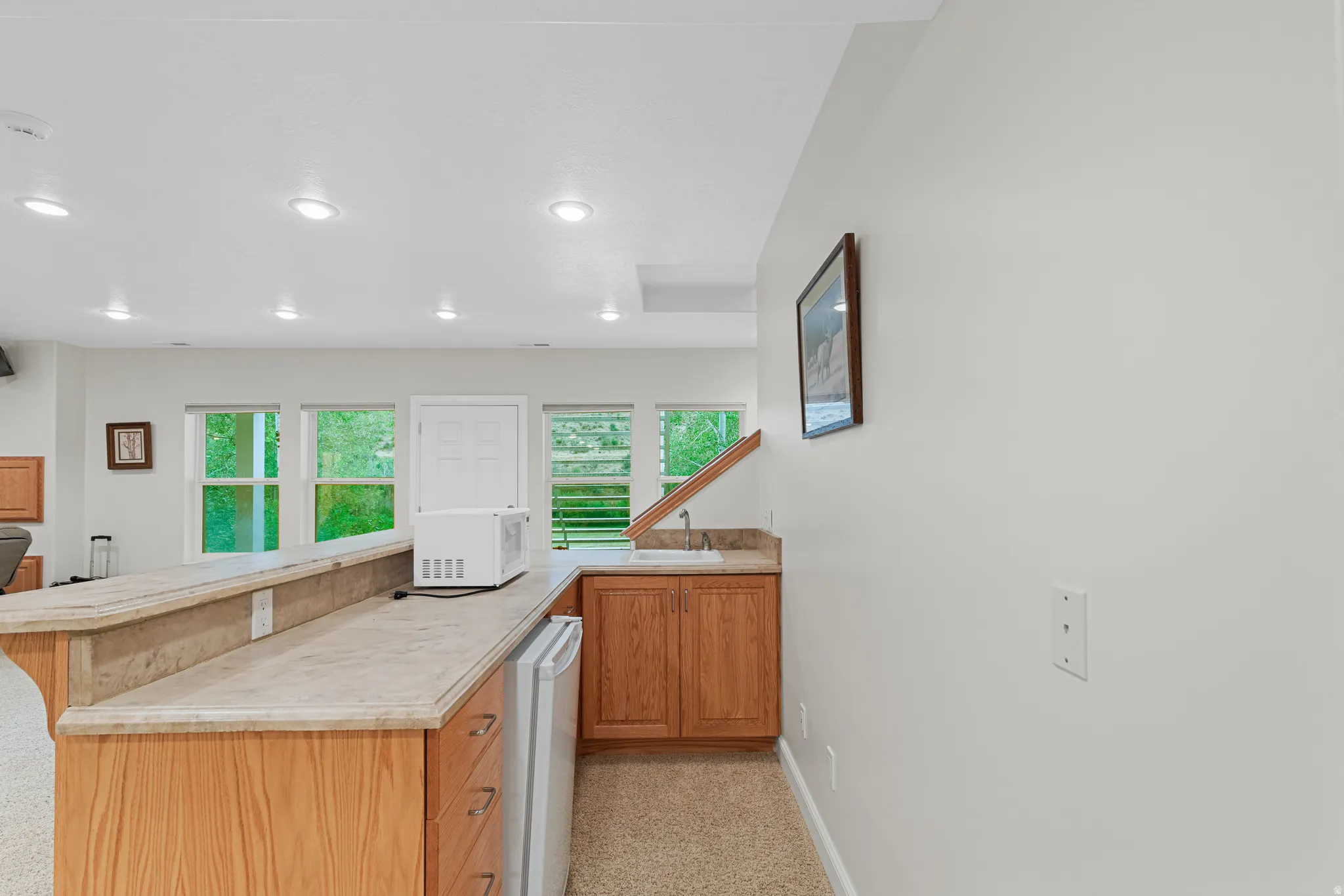 Wet bar featuring wood cabinetry, stone-finish countertops, a built-in sink, and a compact refrigerator