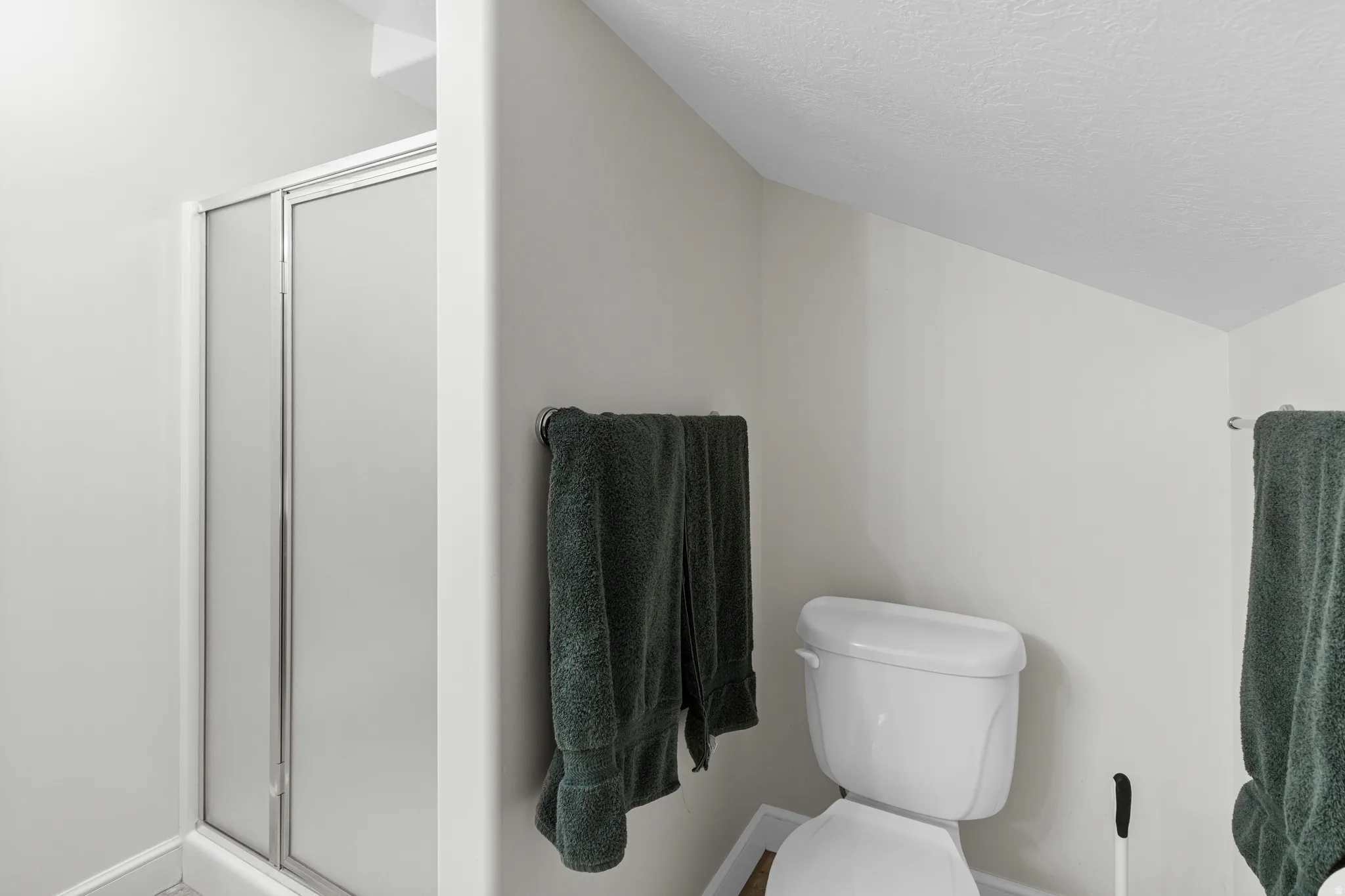 Compact bathroom featuring a shower enclosure with frosted glass doors and a white toilet