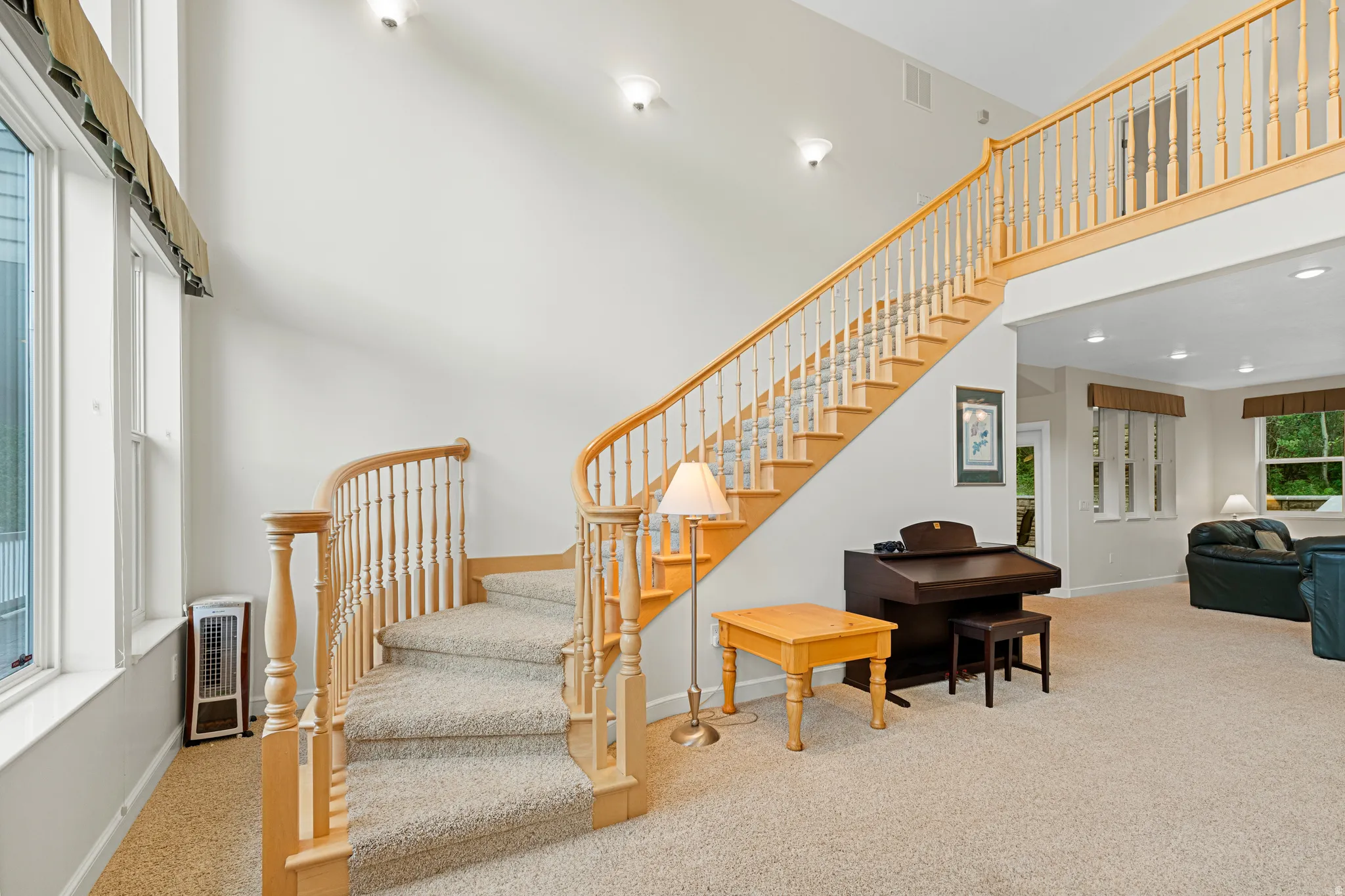 Two-story foyer with a grand staircase featuring wood banisters and carpeted treads