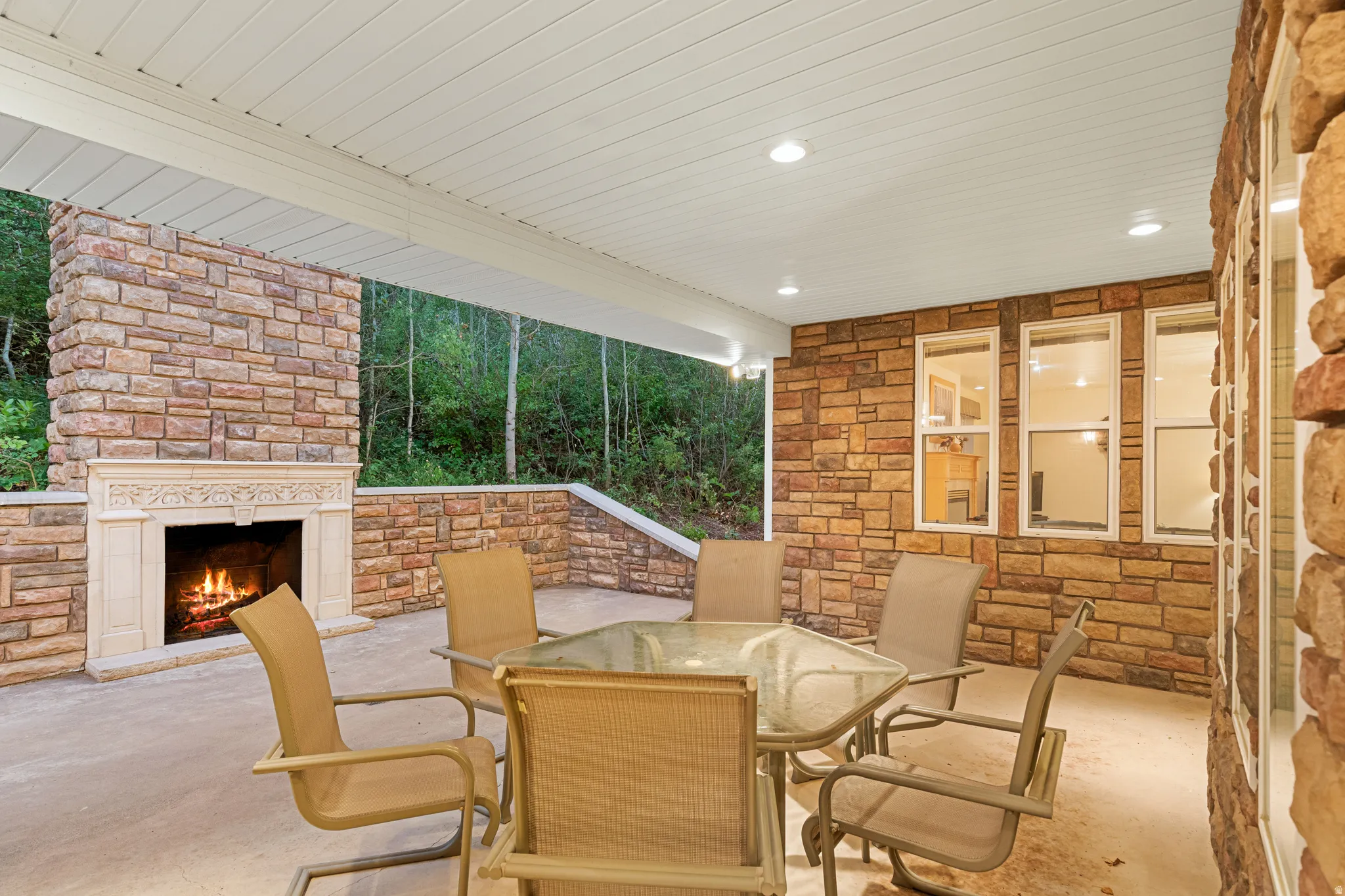 Covered patio featuring a stone-clad exterior with an integrated fireplace and decorative mantel