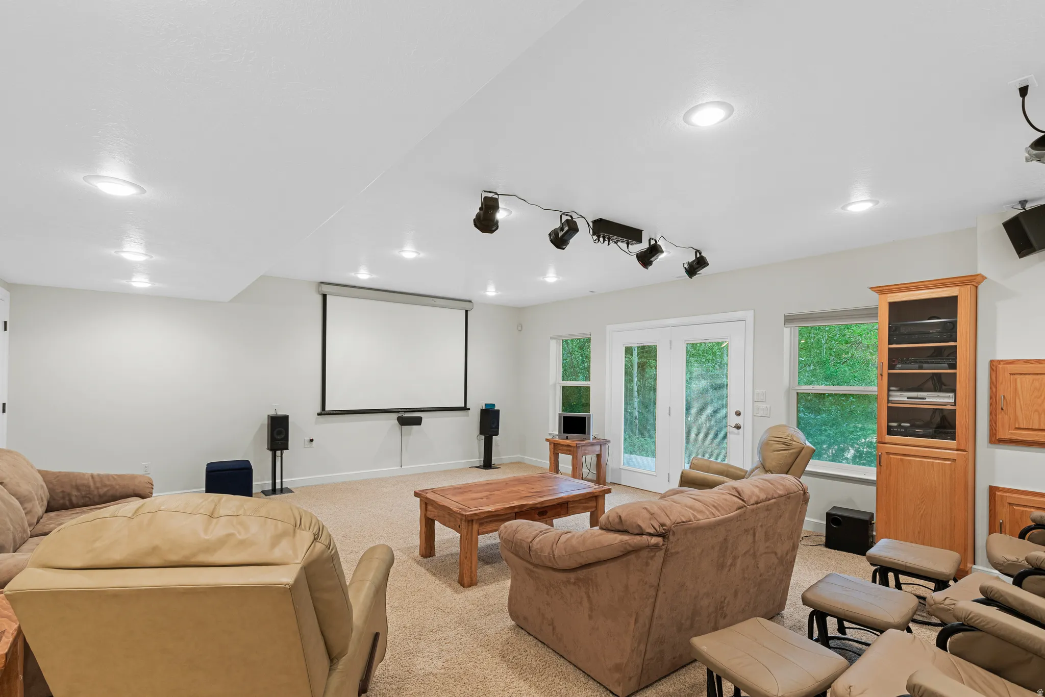 Dedicated entertainment area featuring a projector screen, recessed lighting, and track lighting