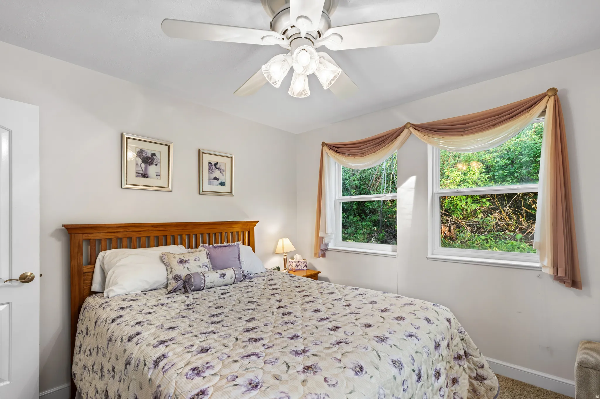 Bedroom featuring twin windows, a ceiling fan with integrated lighting, and light-toned walls