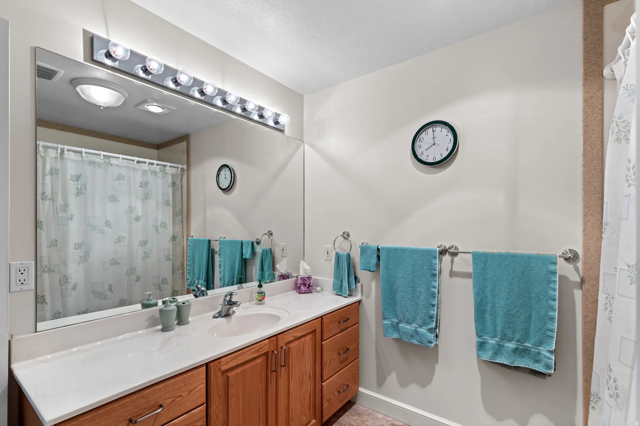 Bathroom vanity featuring a single basin, laminate countertop, and wood-finish cabinetry with silver-tone hardware