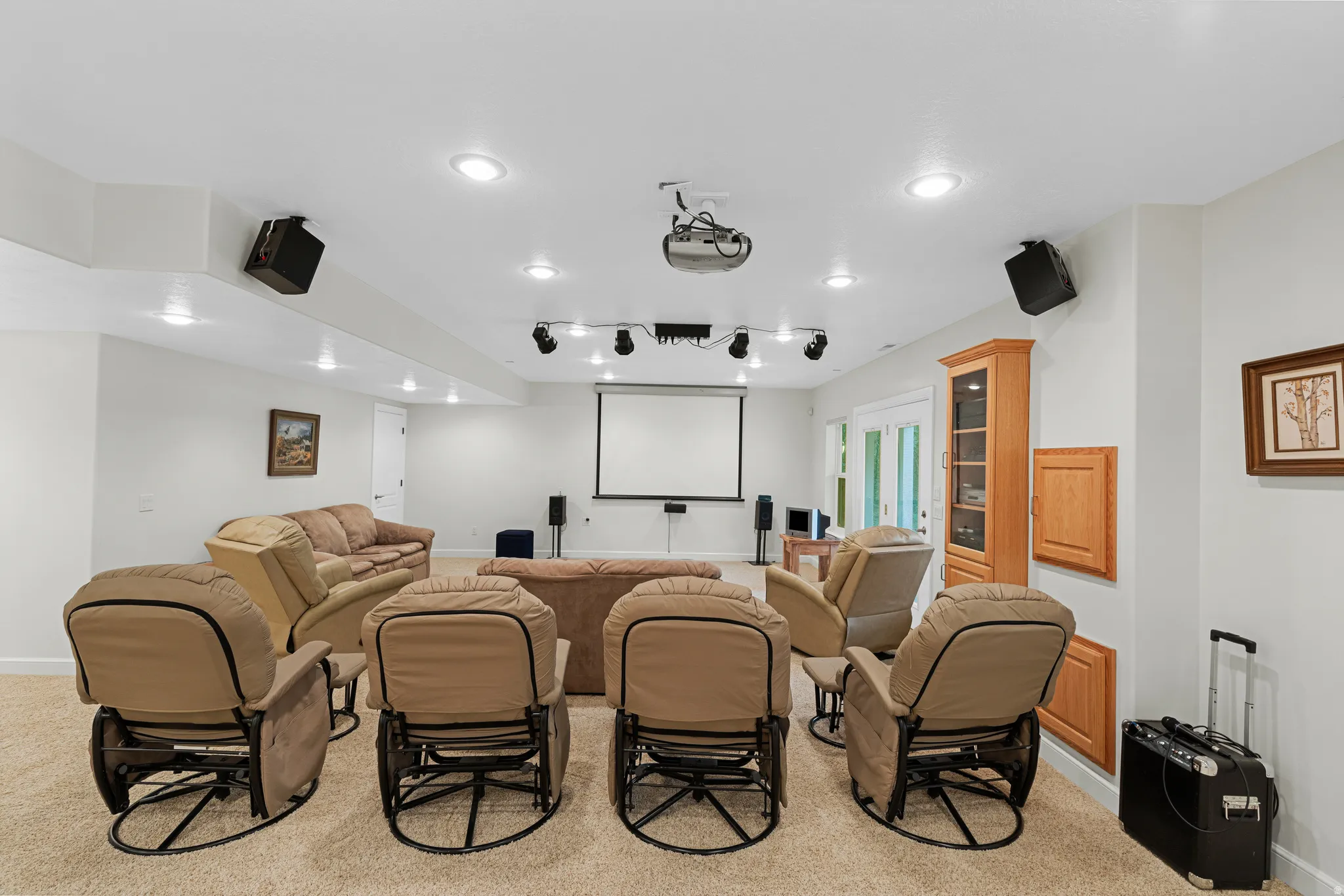 Dedicated media room featuring a large projection screen, recessed lighting, ceiling-mounted speakers, and track lighting