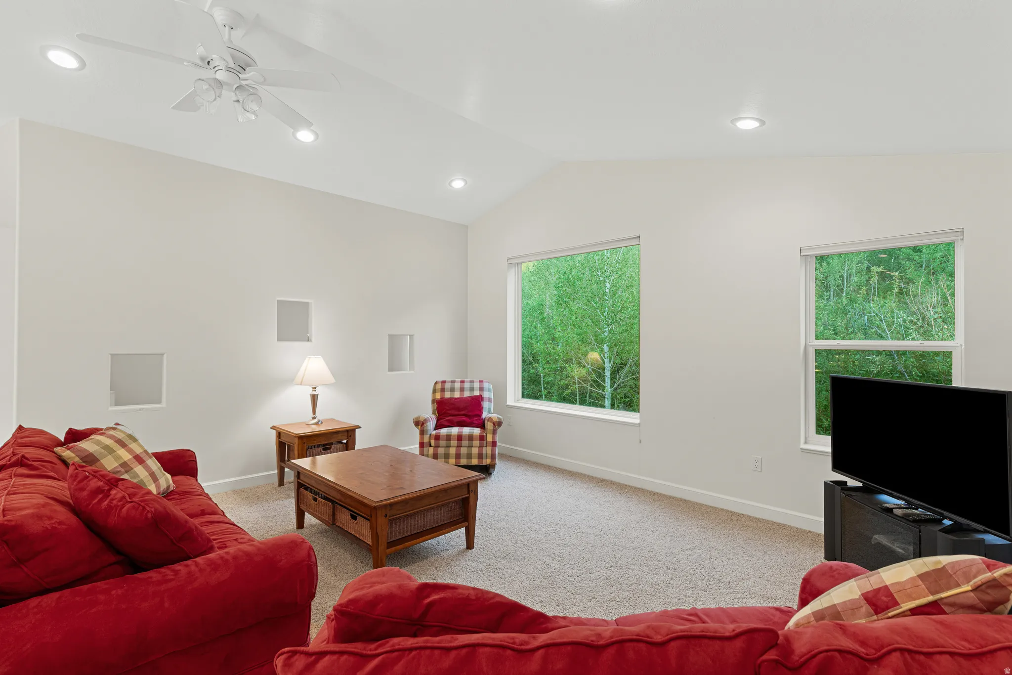 Spacious living area featuring a vaulted ceiling with a ceiling fan, recessed lighting, and light-colored carpeting