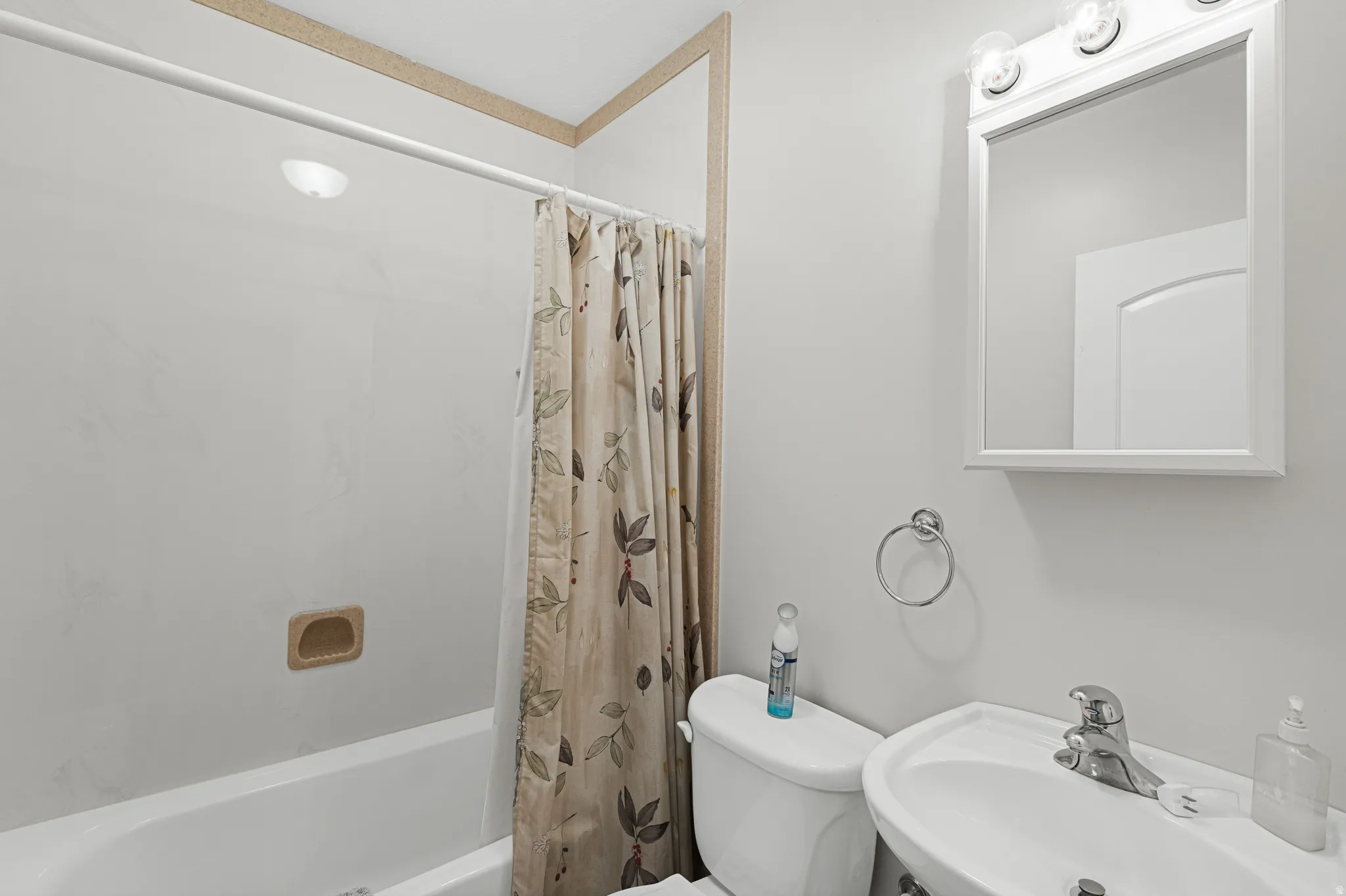 Bathroom featuring a white bathtub, wall-mounted sink, and commode