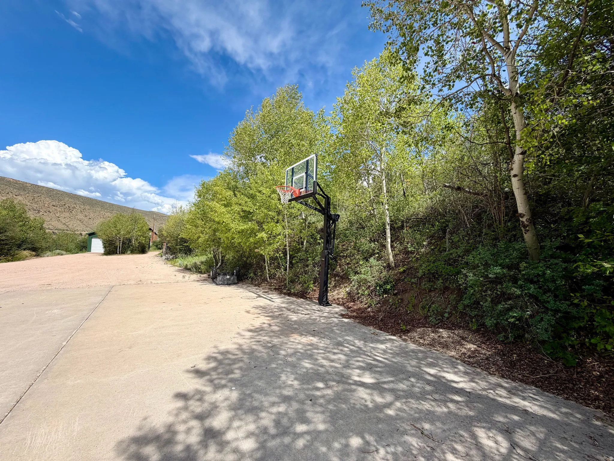 Spacious concrete driveway featuring a basketball hoop