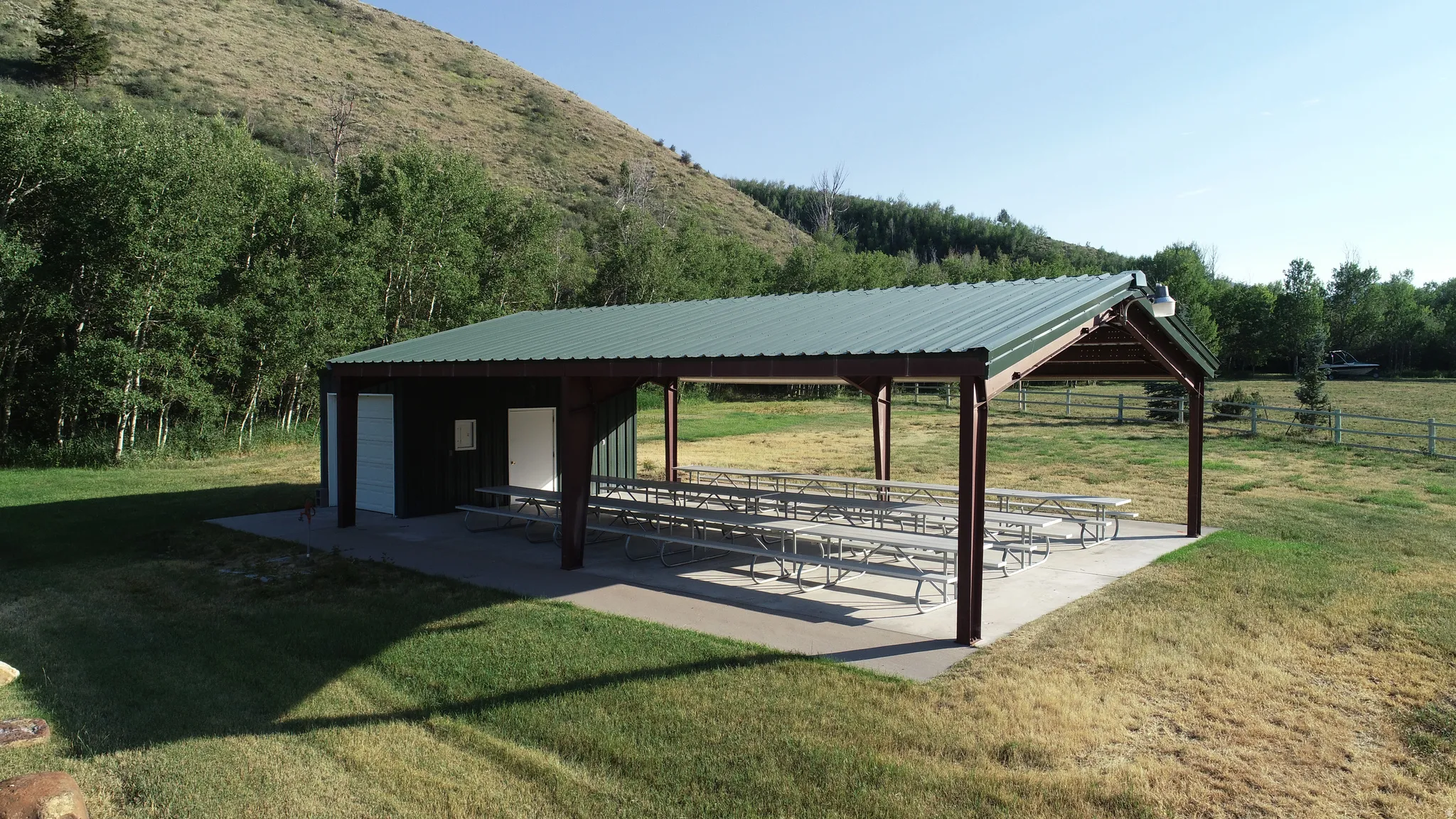 Expansive covered pavilion featuring an enclosed building, substantial support beams, and a concrete slab foundation