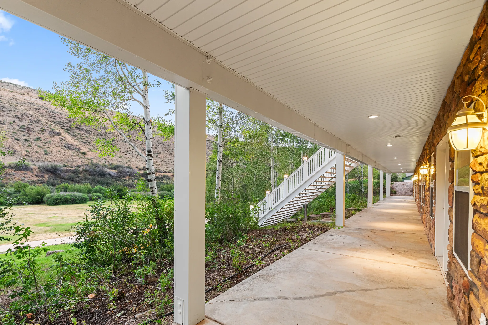 Stone facade walkway with overhead lighting and a white staircase leading to an upper level