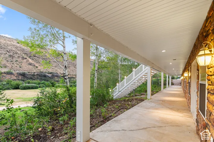 Stone facade walkway with overhead lighting and a white staircase leading to an upper level