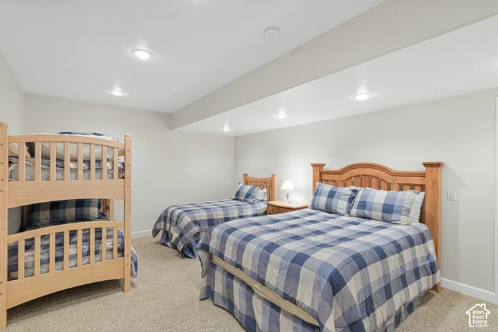 Carpeted room featuring multiple beds, recessed lighting, and light-toned walls