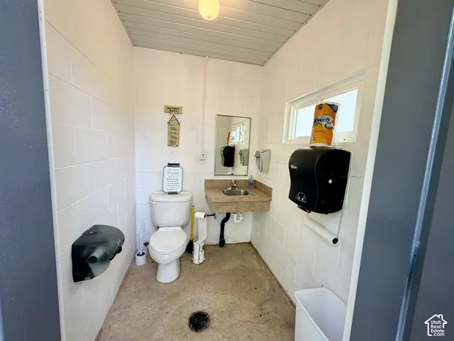Functional restroom featuring white block walls, a single window, and a ceiling-mounted light fixture