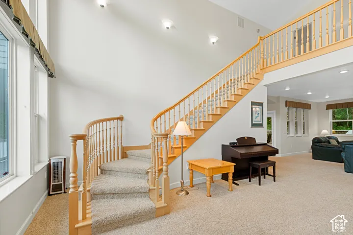 Two-story foyer with a grand staircase featuring wood banisters and carpeted treads