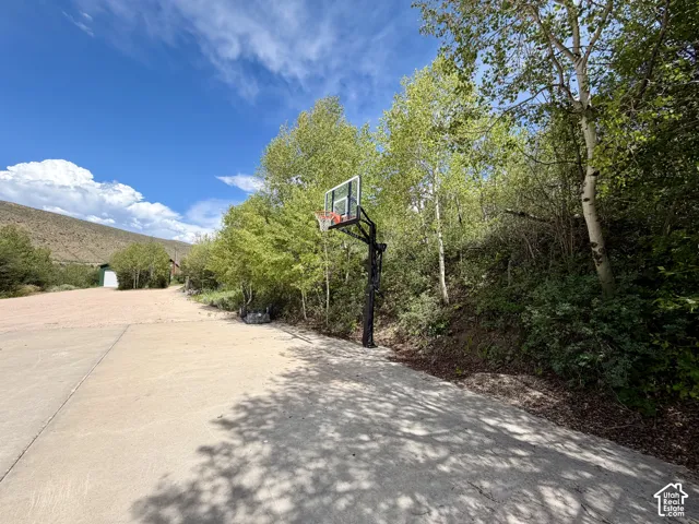 Spacious concrete driveway featuring a basketball hoop