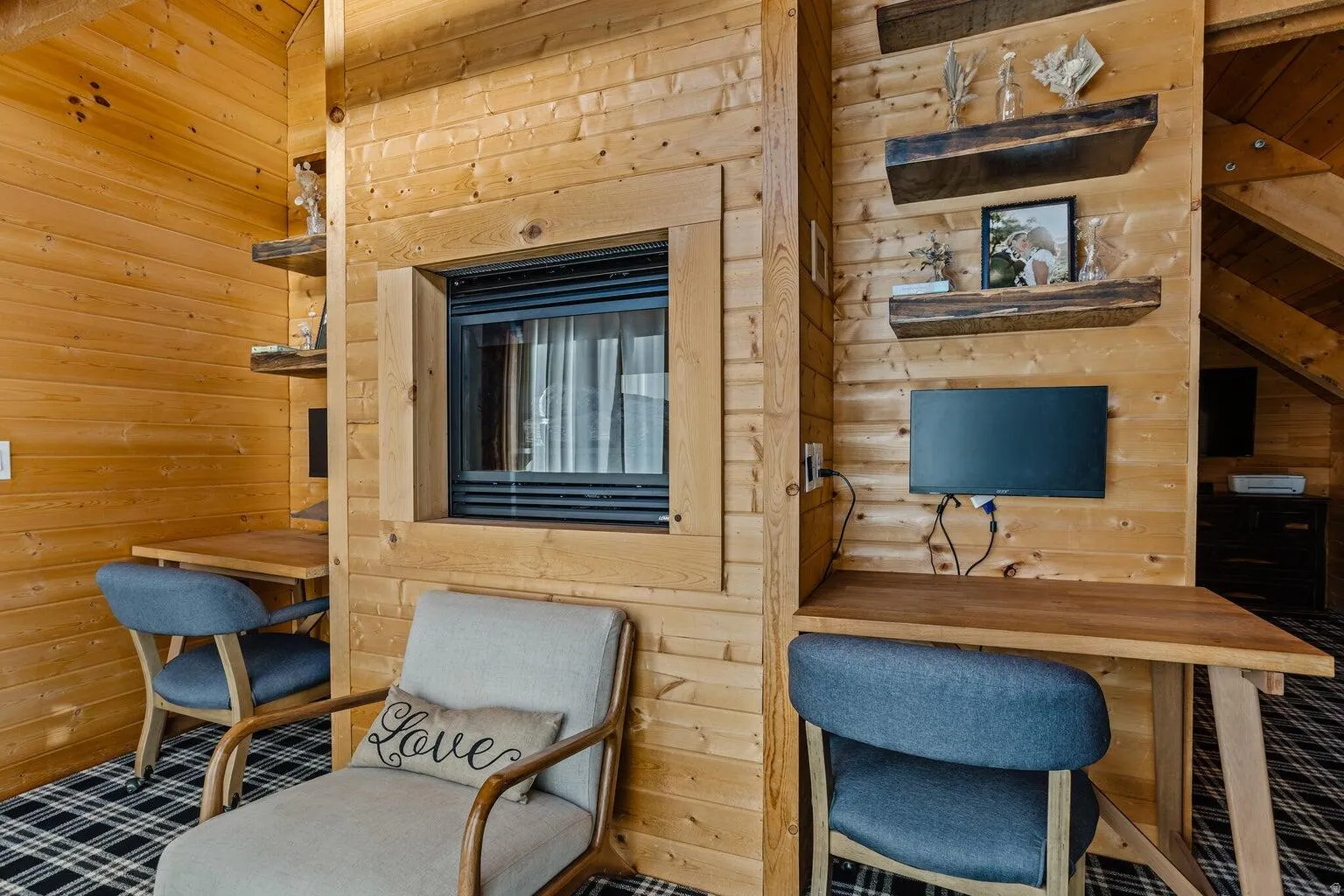 Wood-paneled room featuring a built-in fireplace with a glass front, two integrated desk areas, and floating wooden shelves