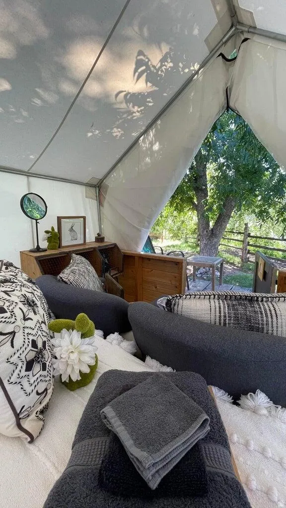 Canvas tent structure featuring a white fabric interior, exposed metal frame, and a large open entry