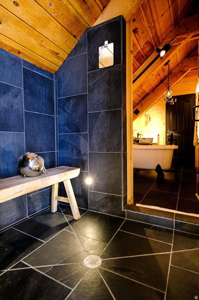 Bathroom featuring a slate tile shower enclosure and flooring, natural wood-paneled sloped ceilings, and recessed lighting