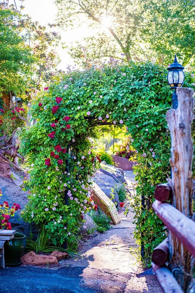 Garden archway with lush green foliage and red and pink climbing roses