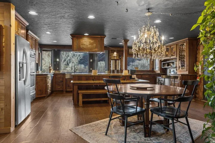 Open-concept kitchen and dining area featuring wood-finish flooring, recessed lighting, and a crystal chandelier