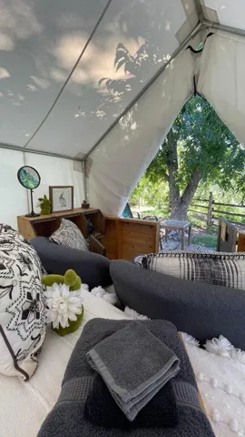 Canvas tent structure featuring a white fabric interior, exposed metal frame, and a large open entry